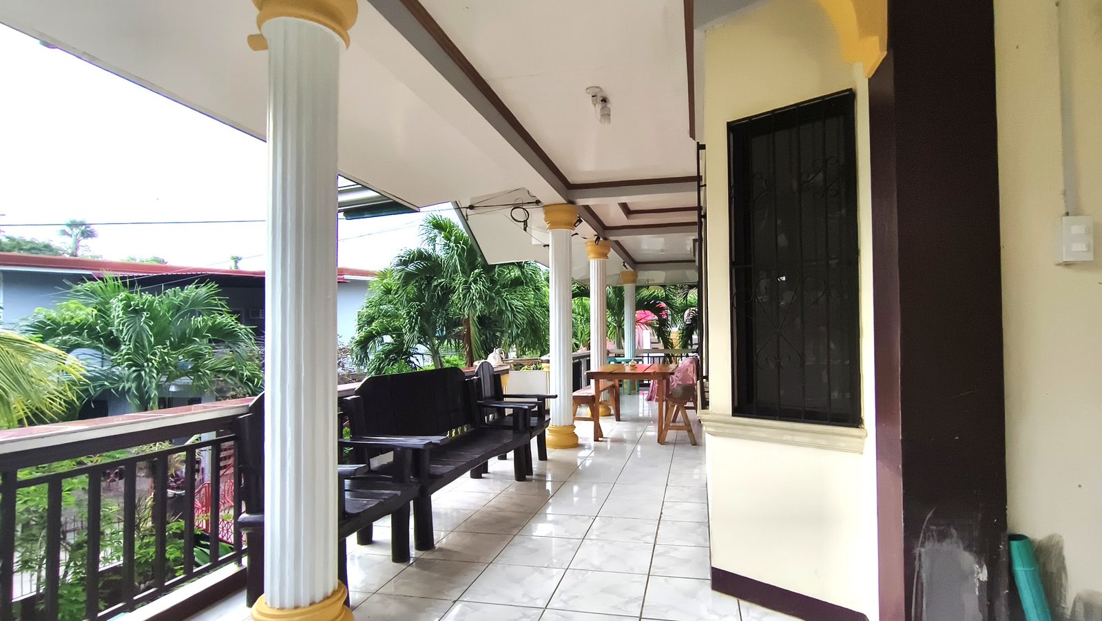 The first-floor balcony, with benches and dining tables looking onto the palms