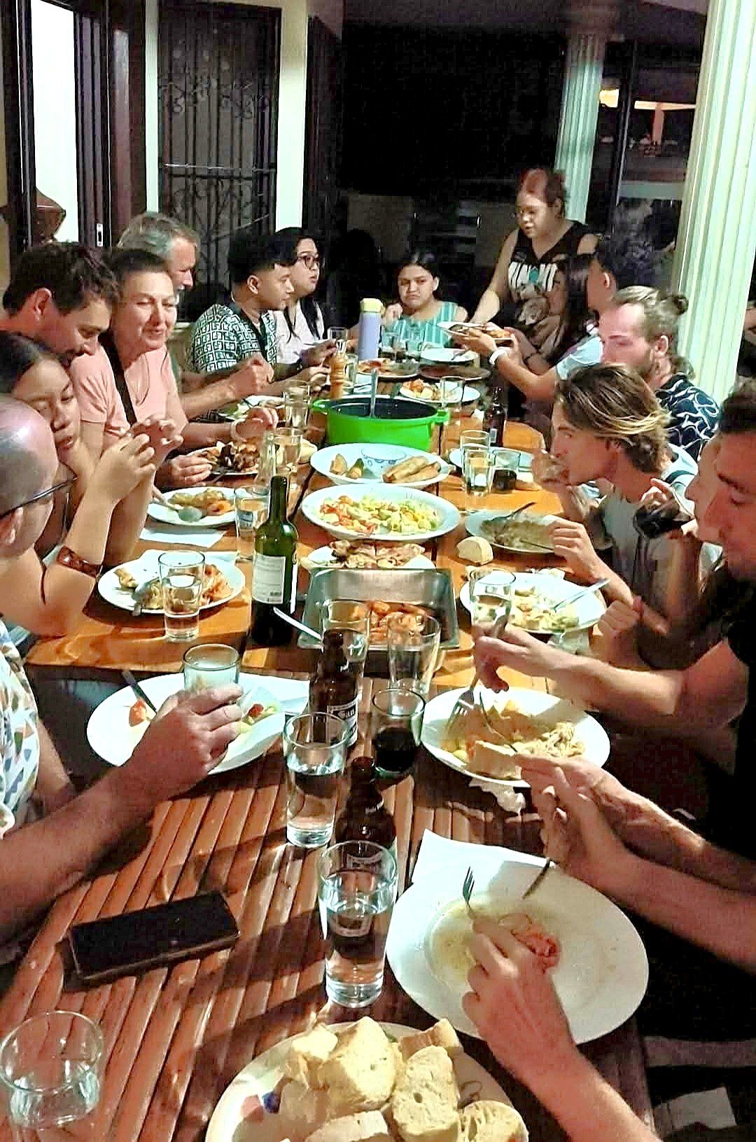 A full table of guests from around the world sharing dinner at Riverside at Aninuan