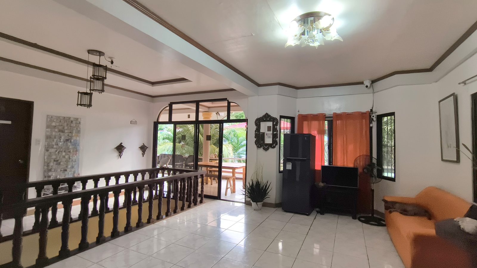 The shared hall, with sofa, TV and doors open to the balcony